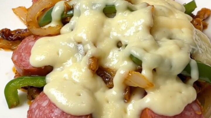 A close-up of slow cooker Philly sausage and peppers topped with melted provolone cheese.