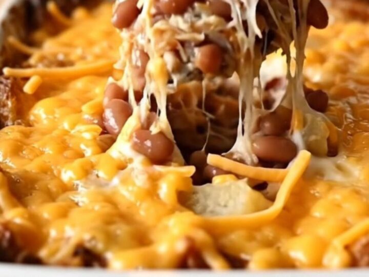 A top-down view of a rectangular baking dish filled with layers of sliced potatoes, ground turkey, beans, and melted cheese.