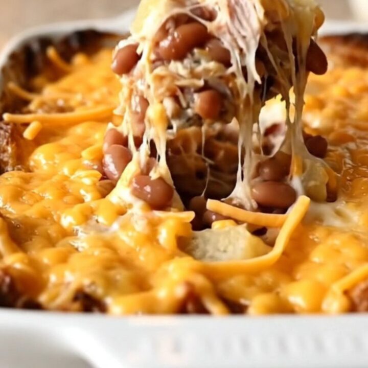 A top-down view of a rectangular baking dish filled with layers of sliced potatoes, ground turkey, beans, and melted cheese.