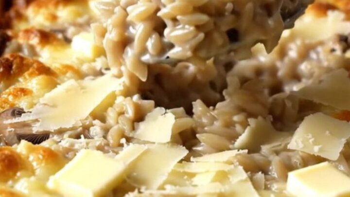 A large rectangular ceramic dish filled with creamy mushroom parmesan orzo, featuring sliced mushrooms and a rich