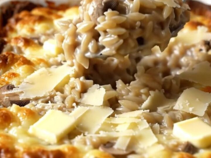 A large rectangular ceramic dish filled with creamy mushroom parmesan orzo, featuring sliced mushrooms and a rich