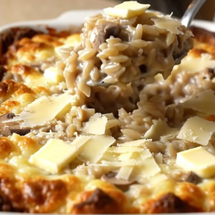 A large rectangular ceramic dish filled with creamy mushroom parmesan orzo, featuring sliced mushrooms and a rich