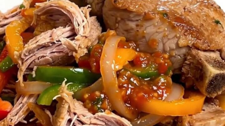 A close-up of tender, shredded fajita pork served on a white plate with colorful peppers and onions.