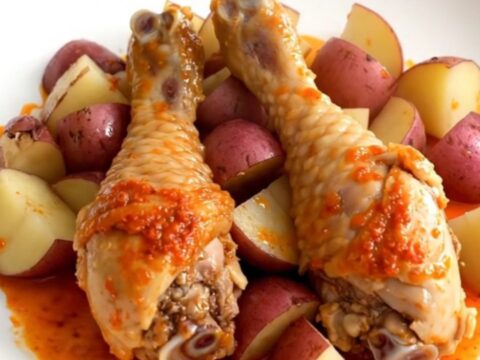 A close-up of tender, skinless chicken drumsticks and quartered red potatoes in a dark slow cooker