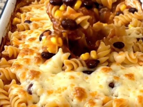 A top-down view of a rectangular white baking dish filled with a colorful rotini pasta bake topped with melted cheese.