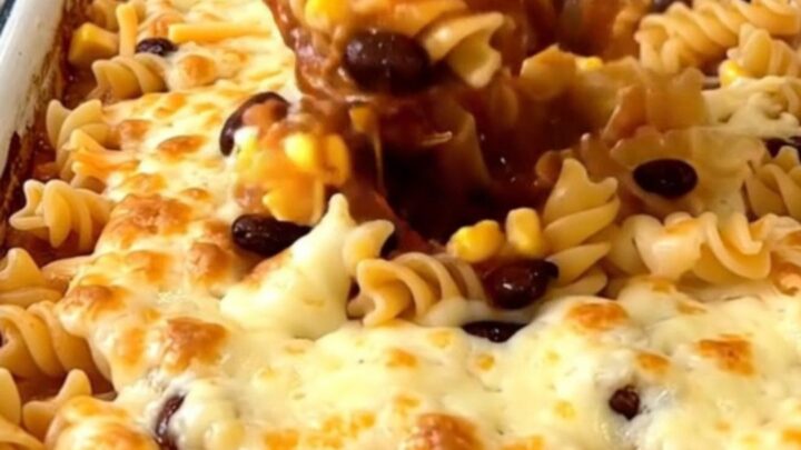 A top-down view of a rectangular white baking dish filled with a colorful rotini pasta bake topped with melted cheese.