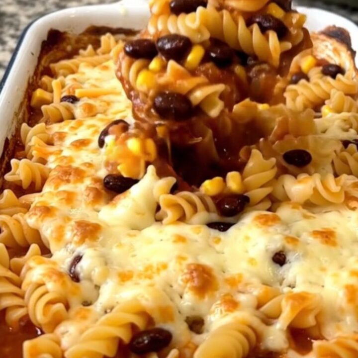 A top-down view of a rectangular white baking dish filled with a colorful rotini pasta bake topped with melted cheese.