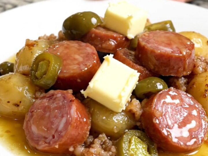 A top-down view of a slow cooker filled with golden potatoes and sliced smoked sausage.