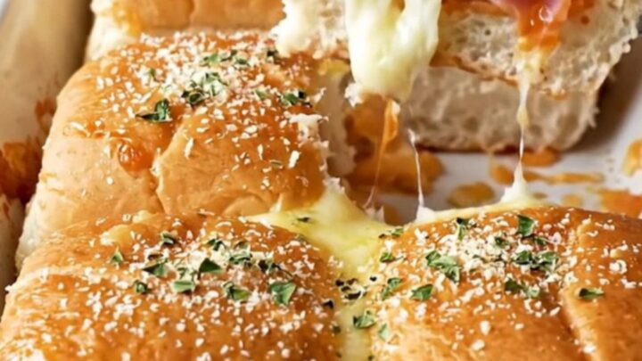 A close-up of Hawaiian pizza sliders in a ceramic baking dish with golden brown tops.