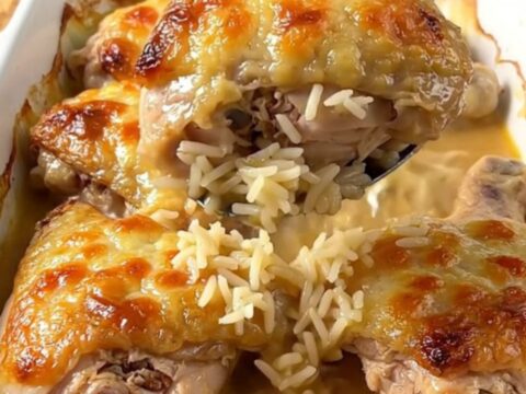 A top-down view of a rectangular baking dish filled with golden baked chicken thighs and savory rice.
