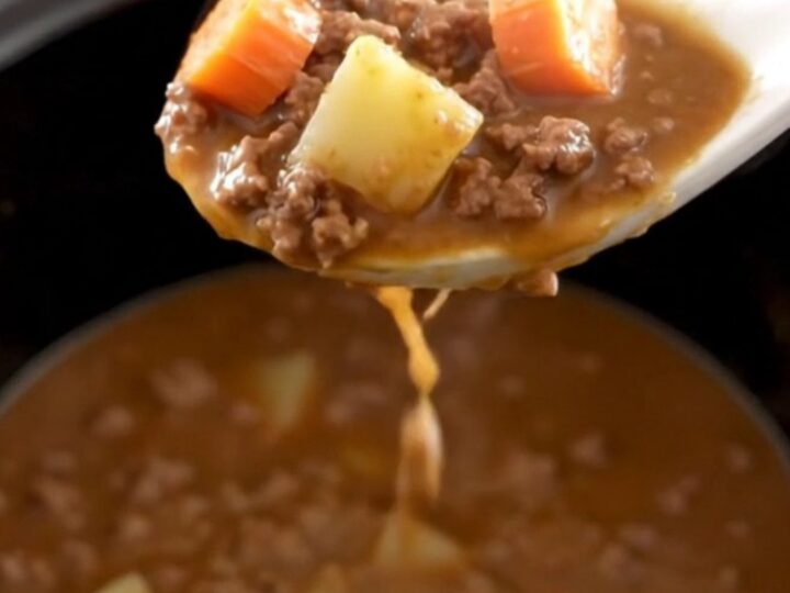 A warm, hearty bowl of slow cooker hamburger stew with chunks of potato, carrots, and ground beef in a rich brown gravy.