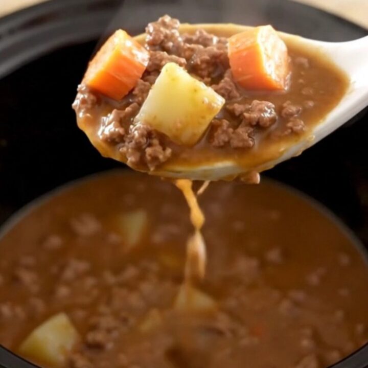 A warm, hearty bowl of slow cooker hamburger stew with chunks of potato, carrots, and ground beef in a rich brown gravy.