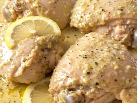A close-up of tender, creamy lemon pepper chicken thighs served on a white plate.