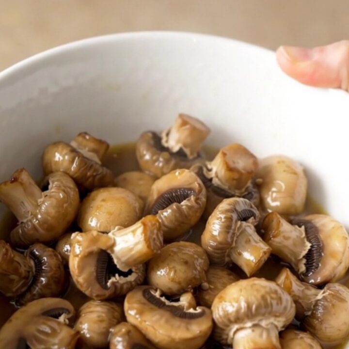 A close-up of tender, whole white button mushrooms glistening in a light garlic butter ranch sauce.