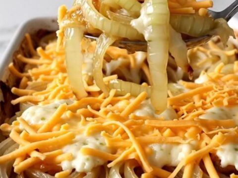 A top-down view of a rectangular baking dish filled with rows of sweet onion slices topped with melted cheese.