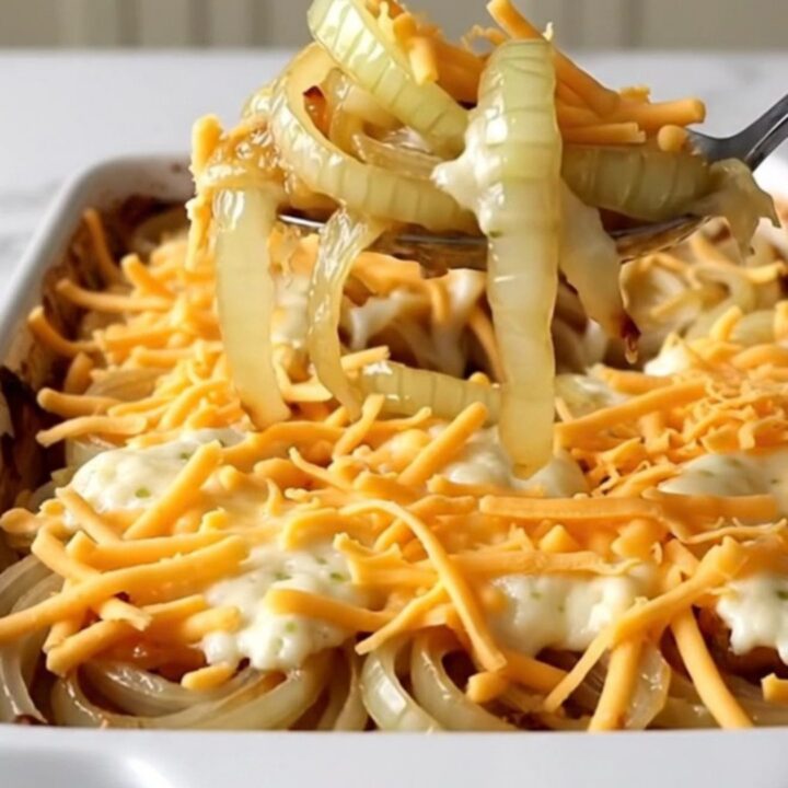 A top-down view of a rectangular baking dish filled with rows of sweet onion slices topped with melted cheese.