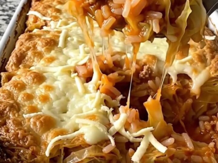 A top-down view of a rectangular baking dish filled with raw cabbage, rice, and ground pork, waiting to be baked.