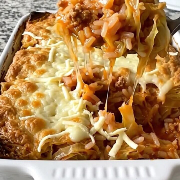 A top-down view of a rectangular baking dish filled with raw cabbage, rice, and ground pork, waiting to be baked.