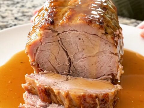 A succulent, slow-cooked pork loin topped with a rich honey soy and Parmesan glaze on a white plate.