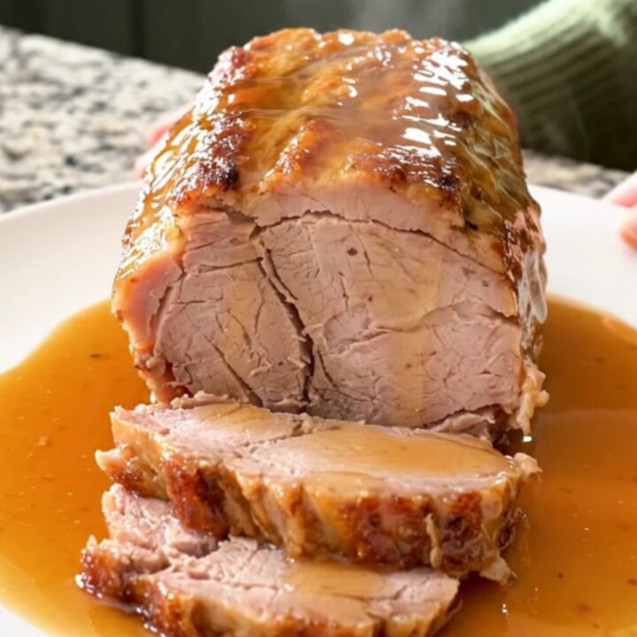 A succulent, slow-cooked pork loin topped with a rich honey soy and Parmesan glaze on a white plate.