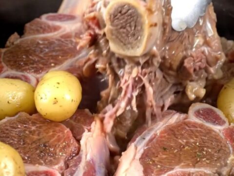Tender beef shanks with baby gold potatoes served in a savory buttery herb broth in a rustic dish.