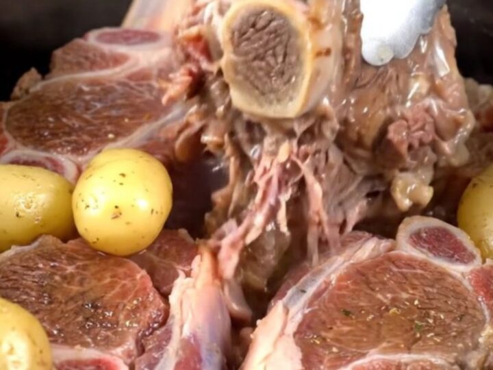 Tender beef shanks with baby gold potatoes served in a savory buttery herb broth in a rustic dish.