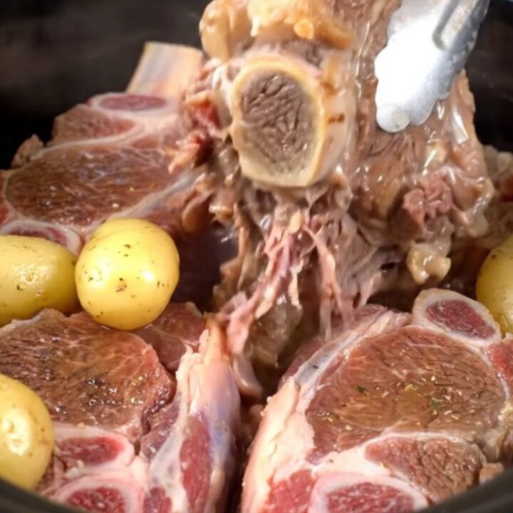 Tender beef shanks with baby gold potatoes served in a savory buttery herb broth in a rustic dish.