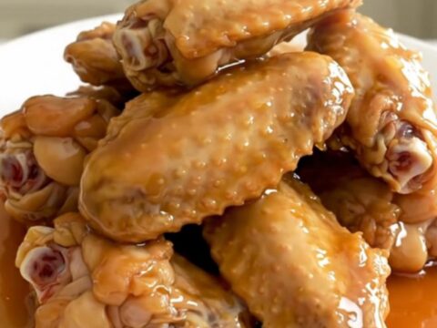 A close-up of tender, glazed honey garlic chicken wings in a slow cooker, showing the rich, sticky sauce.