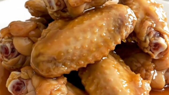 A close-up of tender, glazed honey garlic chicken wings in a slow cooker, showing the rich, sticky sauce.