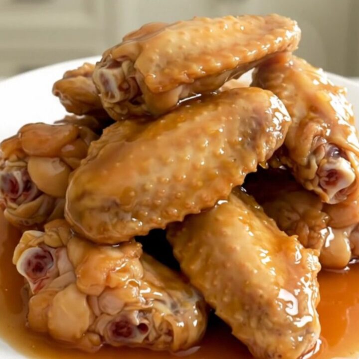 A close-up of tender, glazed honey garlic chicken wings in a slow cooker, showing the rich, sticky sauce.