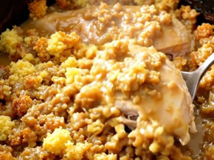 A close-up of slow cooker chicken breasts topped with savory stuffing and gravy in a black ceramic bowl.