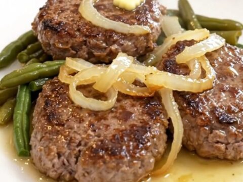Four slow-cooked beef patties with green beans and halved baby potatoes in a slow cooker.