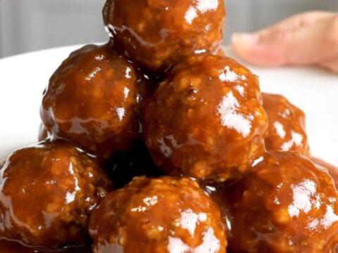 A close-up of honey sriracha turkey meatballs in a slow cooker, looking glossy and glazed.