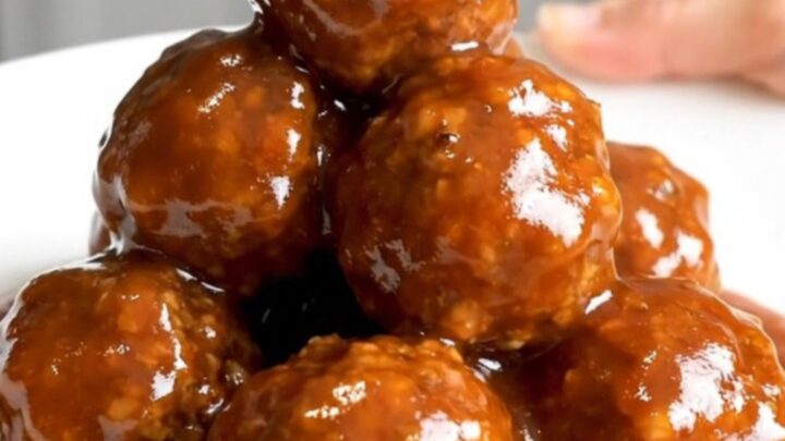 A close-up of honey sriracha turkey meatballs in a slow cooker, looking glossy and glazed.