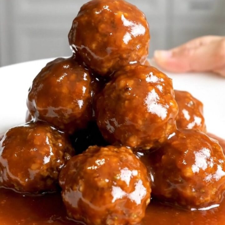 A close-up of honey sriracha turkey meatballs in a slow cooker, looking glossy and glazed.