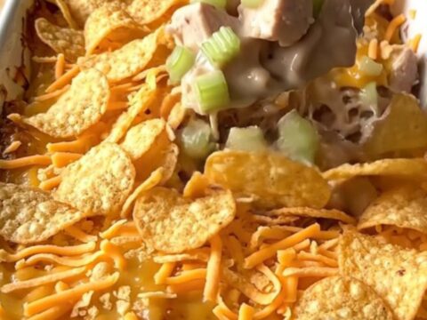 A golden-brown hot chicken salad casserole in a white ceramic dish.