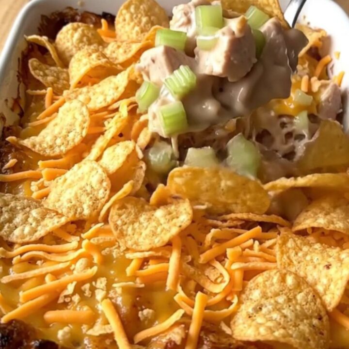A golden-brown hot chicken salad casserole in a white ceramic dish.