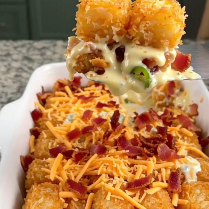 A golden-brown potato tot casserole in a white dish, topped with melted cheddar cheese and crispy bacon.