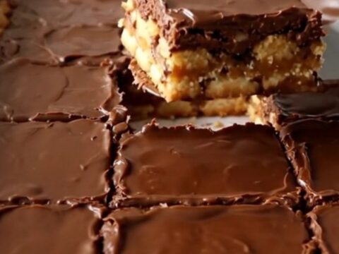 A top-down view of Christmas saltine toffee bars in a white ceramic baking dish, showcasing a golden cracker base.