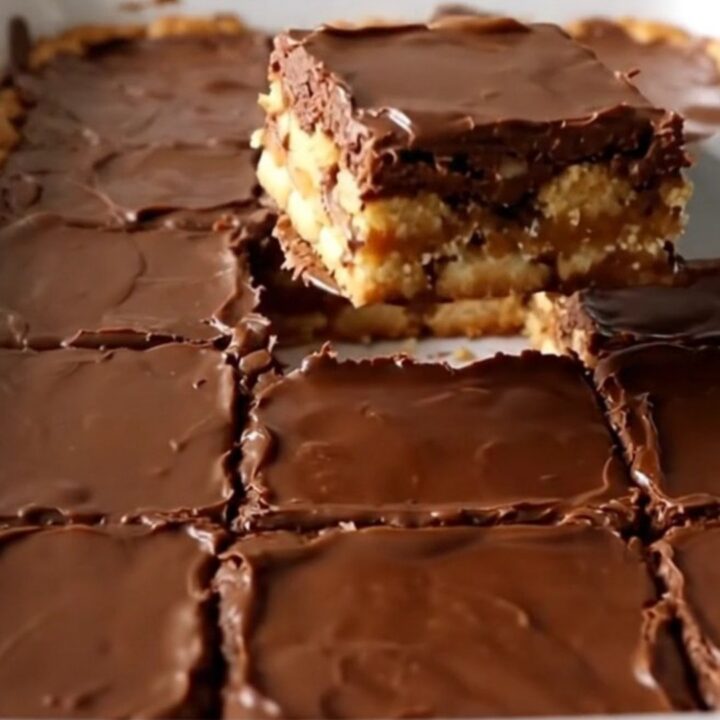 A top-down view of Christmas saltine toffee bars in a white ceramic baking dish, showcasing a golden cracker base.