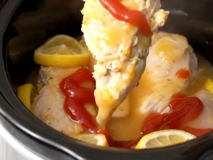 A close-up view of tender, cooked chicken breasts glazed in a glossy, sweet, and tangy lemonade sauce with lemon slices.