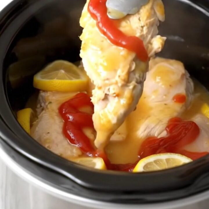 A close-up view of tender, cooked chicken breasts glazed in a glossy, sweet, and tangy lemonade sauce with lemon slices.