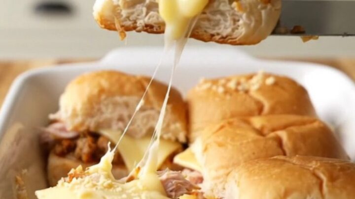 A golden-brown tray of turkey patty melt sliders with melted Swiss cheese and toasted onion tops.