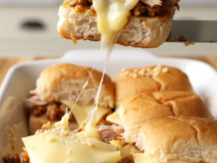 A golden-brown tray of turkey patty melt sliders with melted Swiss cheese and toasted onion tops.