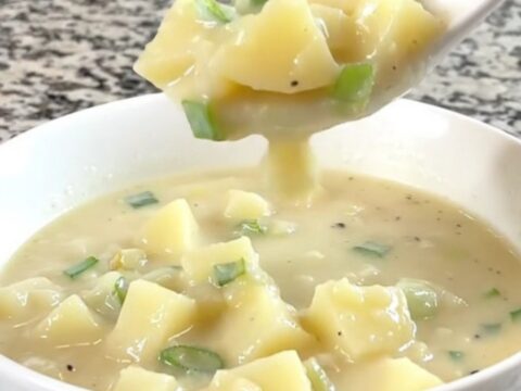 A close-up of a bowl of creamy potato soup garnished with fresh green onions.