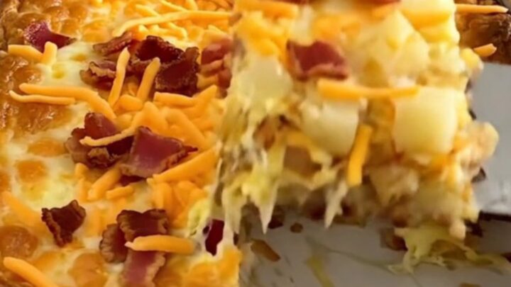 A golden-brown baked breakfast casserole in a white dish, topped with melted cheddar and bacon.