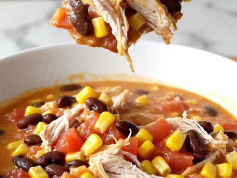 A bowl of creamy slow cooker chicken chili with shredded chicken, beans, and corn.
