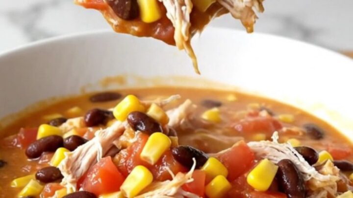A bowl of creamy slow cooker chicken chili with shredded chicken, beans, and corn.