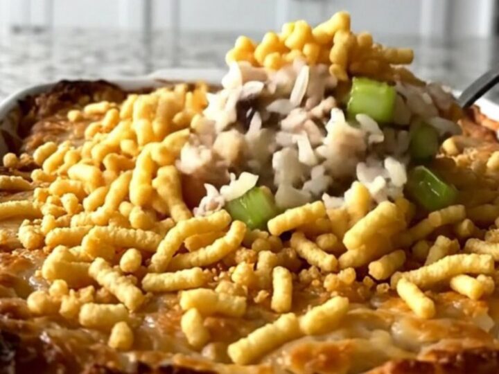 A top-down view of a rectangular baking dish filled with rice, turkey, celery, and a crispy noodle topping.