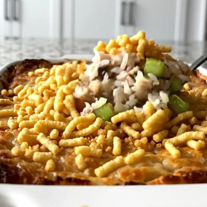 A top-down view of a rectangular baking dish filled with rice, turkey, celery, and a crispy noodle topping.